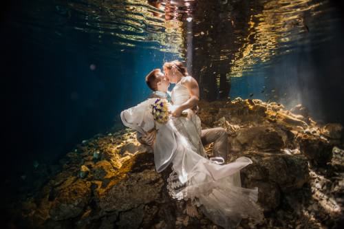 Bride and groom kissing underwater in trash the dress