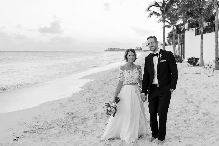 Portrait of bride and groom on beach with bride looking skinner in photograph being behind the groom.