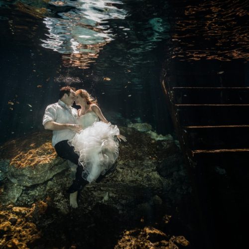 bride and Groom about to kiss in underwater trash the dress in Mayan Cenote at Riviera Maya