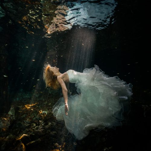 Bride floating to the surface in underwater trash the dress in Mayan Cenote at Riviera Maya