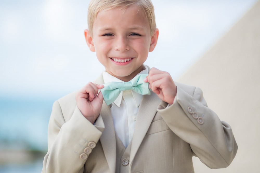 Boy holding bow tie at wedding in Cancun
