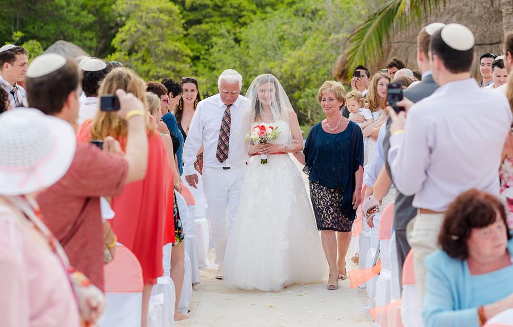 Bride walking down aisle with parents.