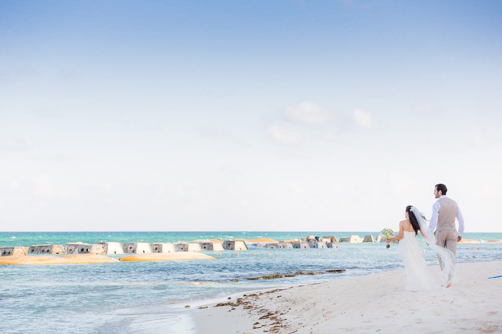 Bride and groom walking on beach at generations Riviera Maya Wedding