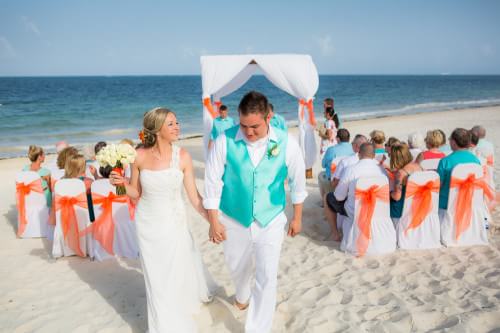 Couple walking down the aisle at their Ocean Coral and Turquesa Wedding