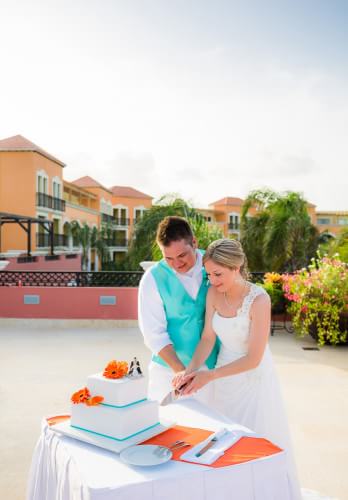 Couple cutting wedding cake at Ocean Coral and Turquesa Resort
