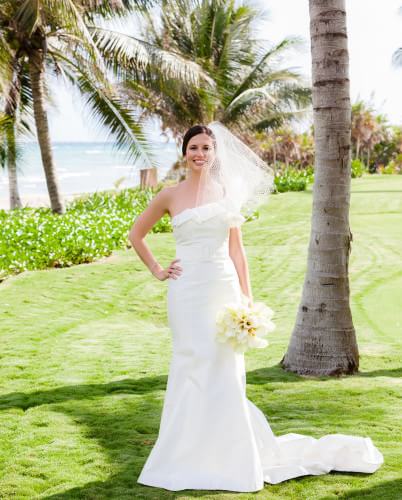 Bride wearing wedding dress on grass near beach in Riviera Maya