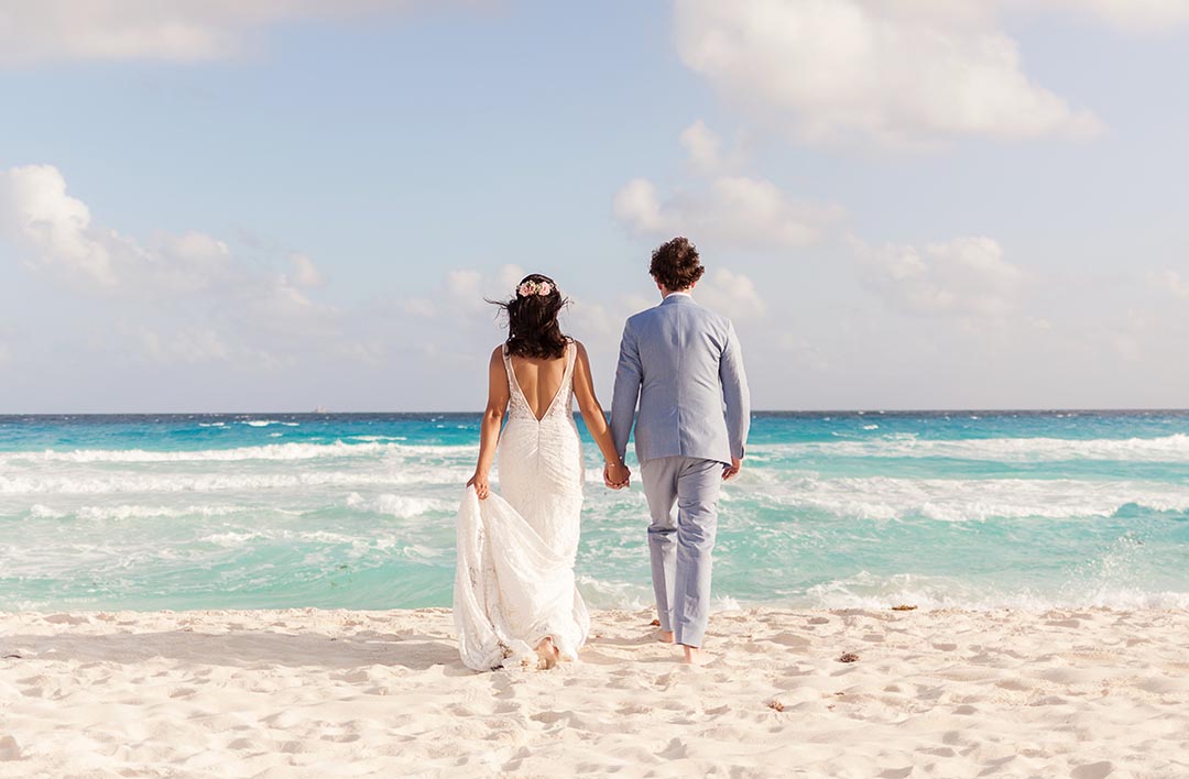 Bride and Groom holding hands walking on beach in Cancun