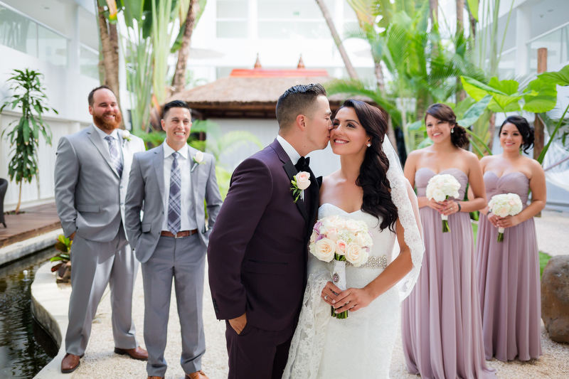 Groom kissing bride in garden at Playacar Palace Resort , Playa del carmen
