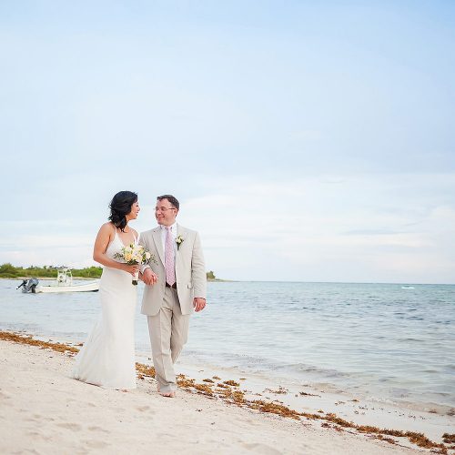 Bride and groom walking on beach in Tulum