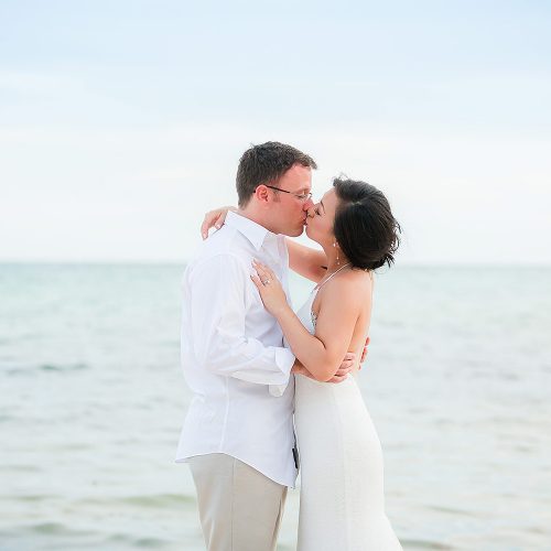 Bride and groom kissing on beach in Tulum