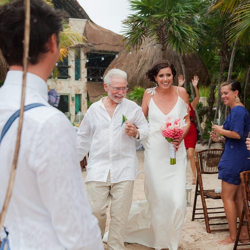 Bride walking down beach as it starts to rain in Riviera Maya