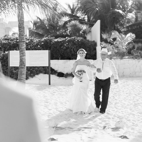 Bride walking down aisle at beach wedding ceremony at Excellence Playa Mujeres