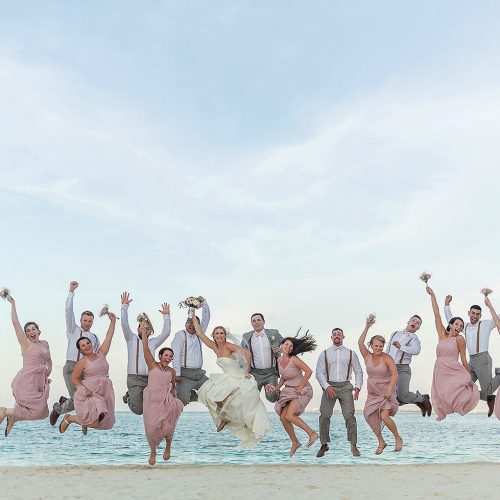 Bridal party jumping on beach after wedding at Excellence Playa Mujeres