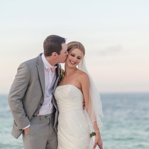 Groom kissing bride beach at Excellence Playa Mujeres resort wedding