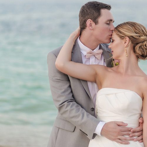 Bride and groom kissing on beach after wedding