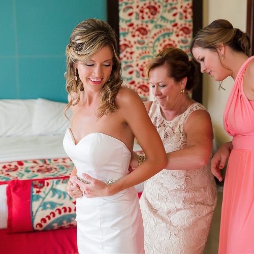Mother of bride helping bride put on dress at NOW Jade Riviera Cancun
