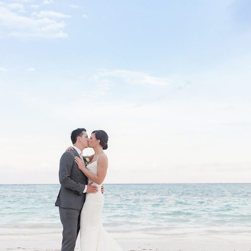 Bride and groom kissing on beach at Secrets Akumal Riviera Maya