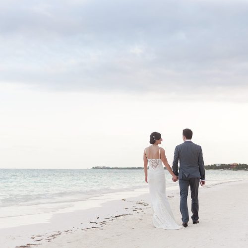 Bride and groom walking on beach at Secrets Akumal Riviera Maya