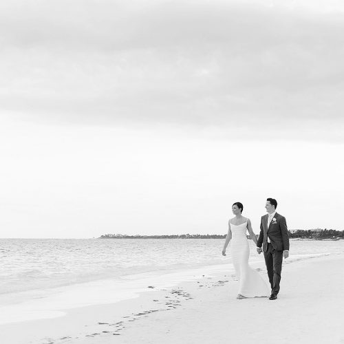 Bride and groom walking on beach at Secrets Akumal Riviera Maya