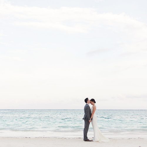 Bride and groom kissing on beach at Secrets Akumal Riviera Maya