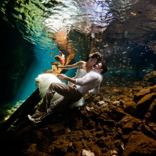 Bride and groom laying down underwater in Mayan Cenote Trash the Dress