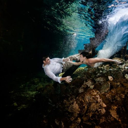 Bride and groom swimming under water in mayan cenote Trash the Dress.