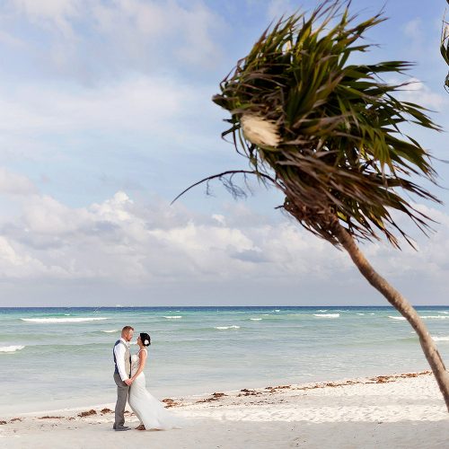 Bride and Groom on the beach with palm tree at Playa del Carmen beach wedding