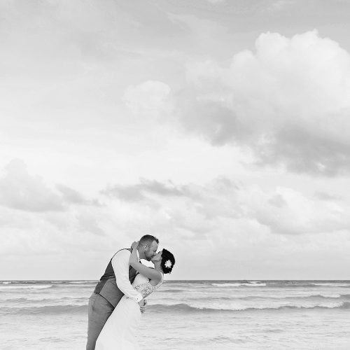 Black and white photography of bride and groom kissing on the beach at Playa del Carmen wedding