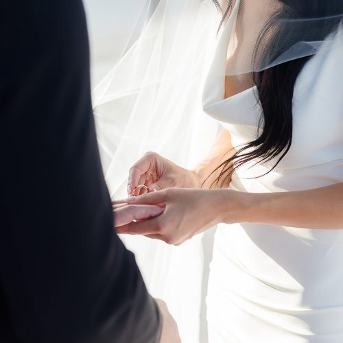 Close up of bride putting on grooms ring