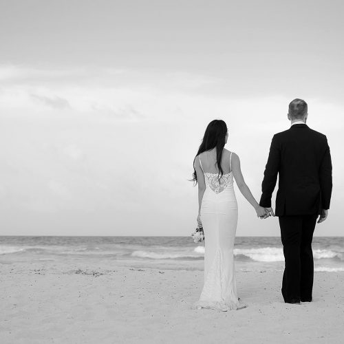 Bride and groom holding hands on beach at Secrets The Vine Cancun
