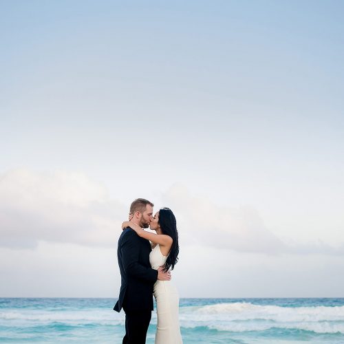 Bride and groom kissing on beach at Secrets The Vine Cancun wedding
