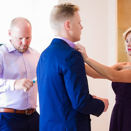 Bridesmaid helping groom before gay wedding