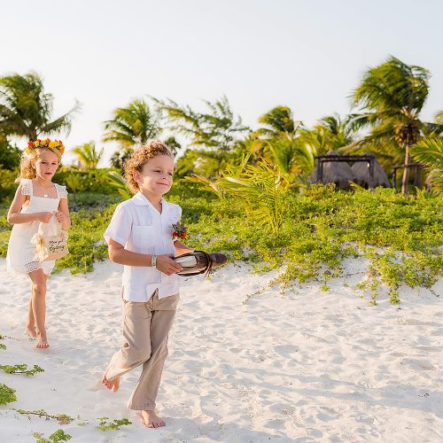 Flower girls and ring bearer walk down sand aisle in Tulum