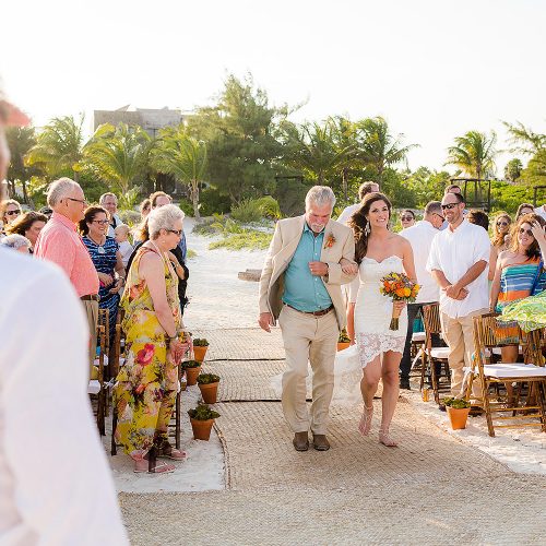 Bride and father walk down sand aisle at beach wedding in Tulum