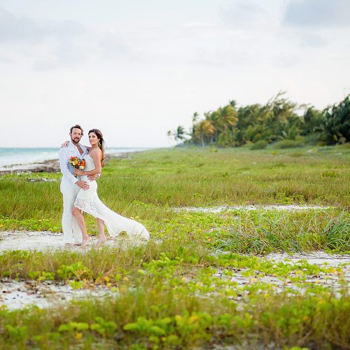 Portrait of Bride and groom in grass near beach after wedding in Tulum