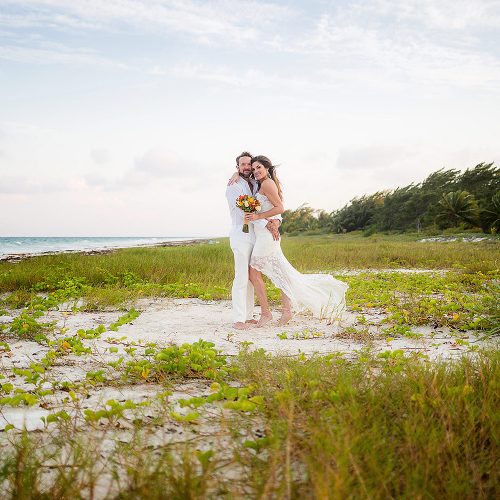 Portrait of Bride and groom in grass near beach after wedding in Tulum