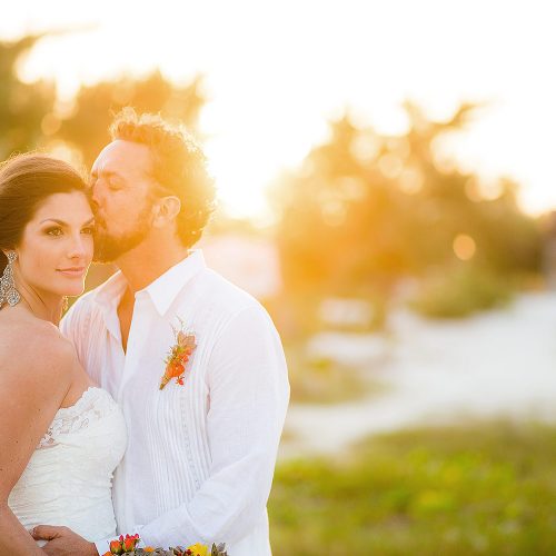 Groom kissing bride in beautiful sunset