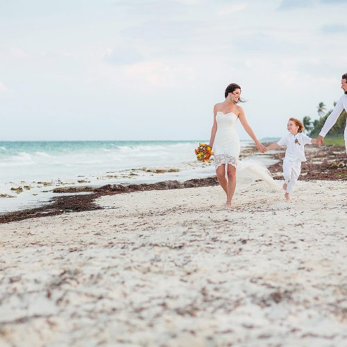 Bride and groom walking with son after wedding in Tulum