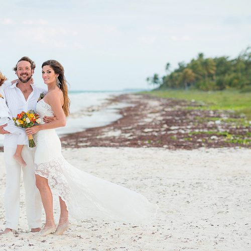 Groom holding son with bride after wedding in Tulum