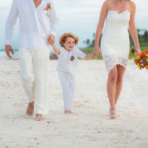 Bride and groom walking with son after wedding in Tulum