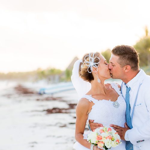 Bride and groom kissing on beach in Tulum