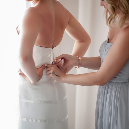 Close up of bride putting on dress