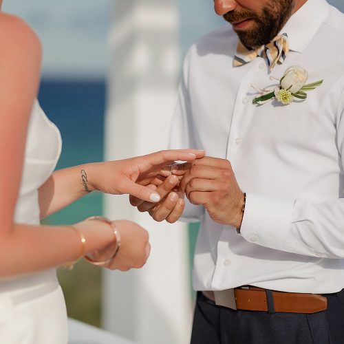 Close up of groom putting on ring at wedding ceremony