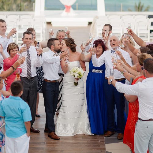 Bride and groom kissing with guests all around