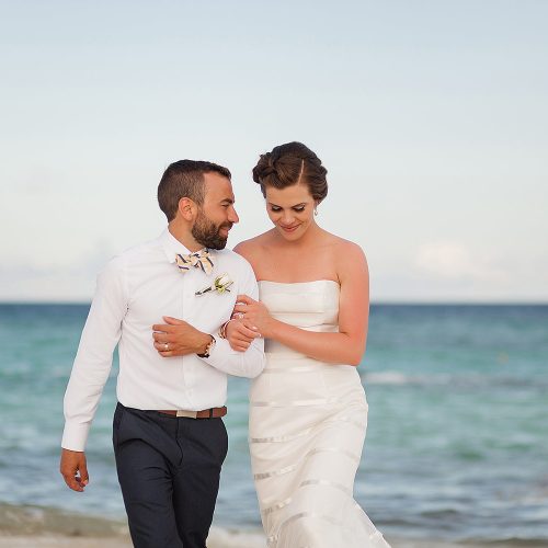 Close up of bride and groom walking on beach.