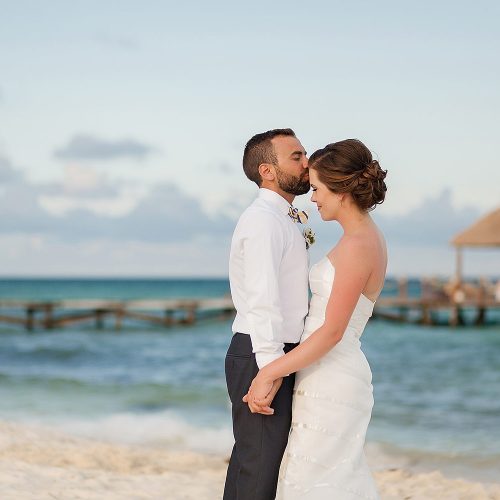 Groom kissing bride on beach at Azul Fives Hotel, Riviera Maya