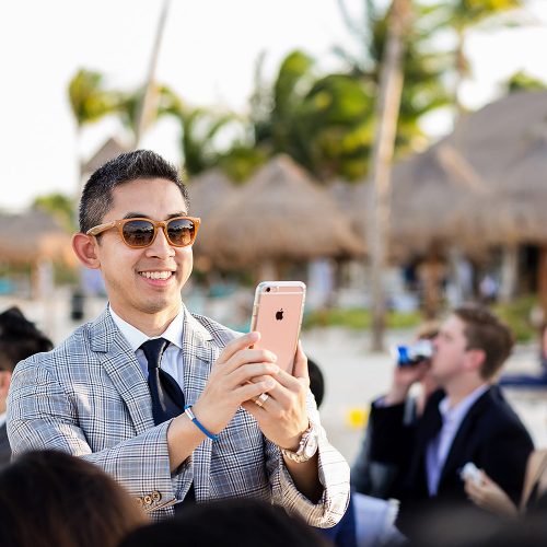Guest taking photo with phone at wedding ceremony in Cancun