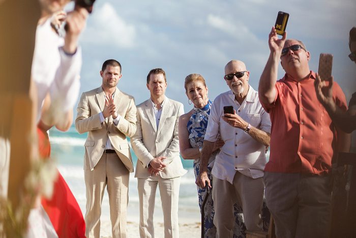 Guests taking photographs with phones as bride walks down the aisle in Tulum wedding