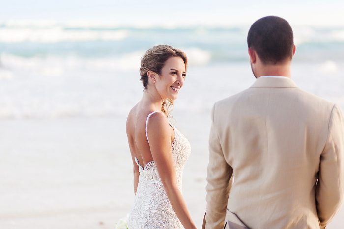 Bride looking at groom on beach in Tulum