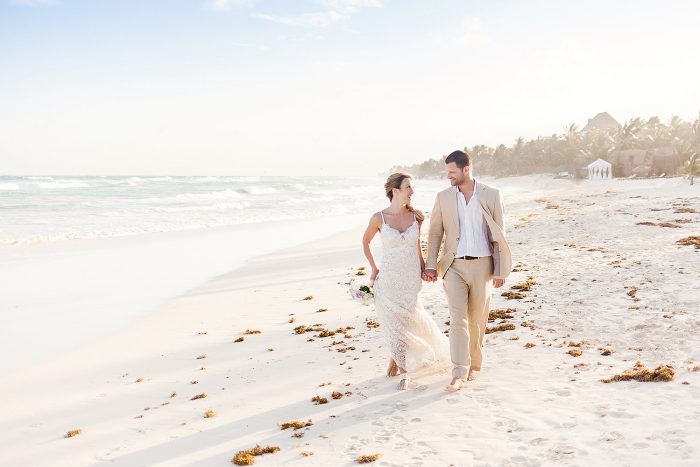 Bride and groom walking down beach in Tulum